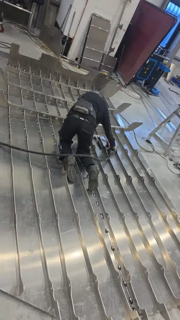Opbouw van een aluminium sloepcasco: spanten uit het snijpakket worden op de bodemplaat geplaatst